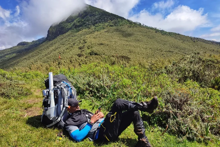 Hiker resting on a green hillside in Kenya
